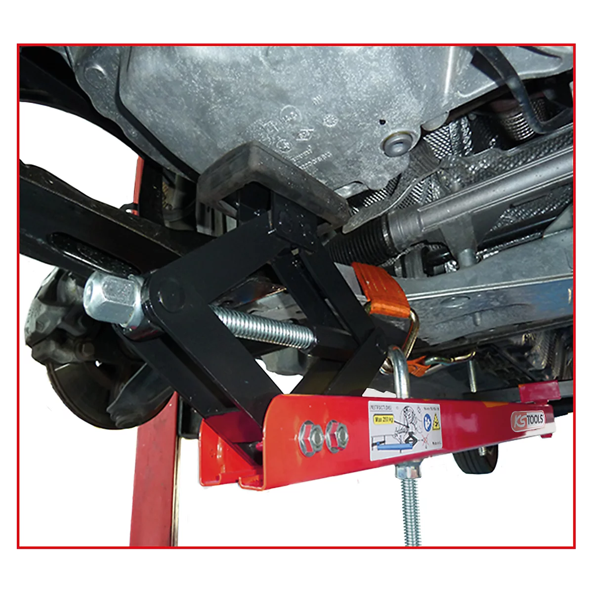 Ein schwarzer Wagenheber stützt ein Fahrzeug von unten ab. Darunterliegend rot-silberne Metallteile.